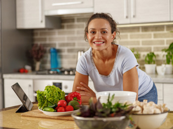 Mujer hispana en la cocina con platos de vegetales