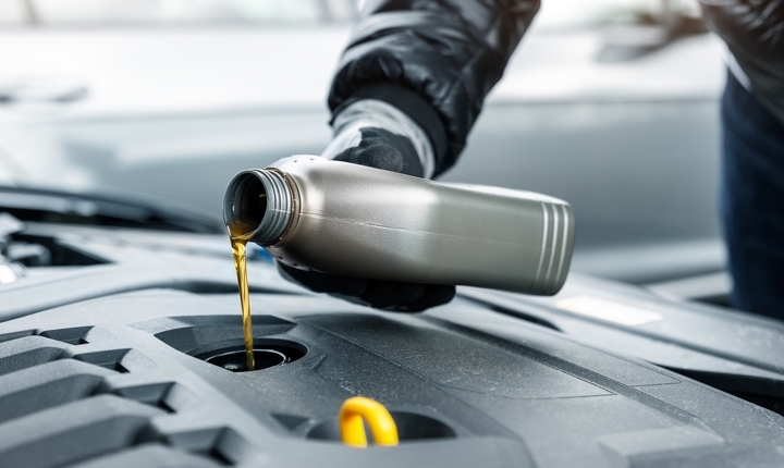 Persona poniendo aceite a un carro