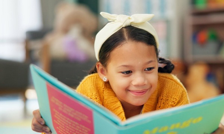 Niña latina leyendo un libro infantil