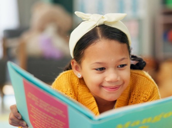 Niña latina leyendo un libro infantil