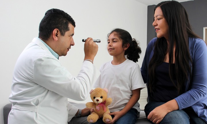 Doctor revisando la vista de una niña latina