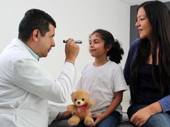 Doctor revisando la vista de una niña latina