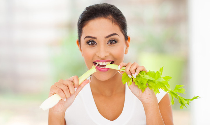 Una joven latina comiendo una rama de apio