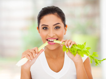 Una joven latina comiendo una rama de apio