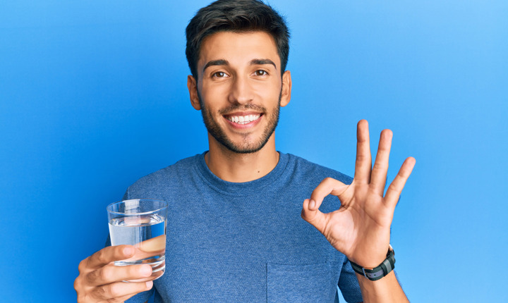 Hombre joven con un vaso de agua en la mano