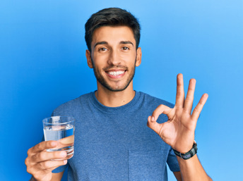 Hombre joven con un vaso de agua en la mano