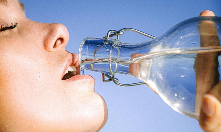 Mujer tomando agua en un día de verano