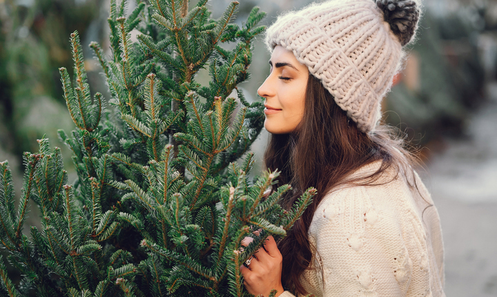 Mujer oliendo un pino de Navidad