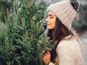 Mujer oliendo un pino de Navidad