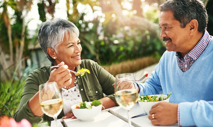 Pareja de adultos hispanos comiendo una ensalada