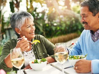 Pareja de adultos hispanos comiendo una ensalada