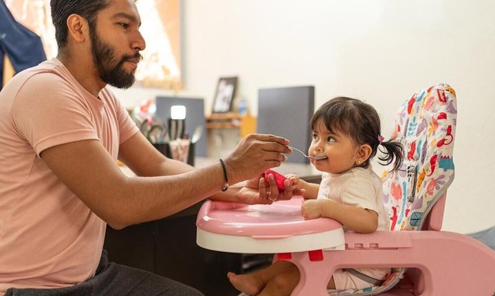 Papá dándole de comer a su hija pequeña