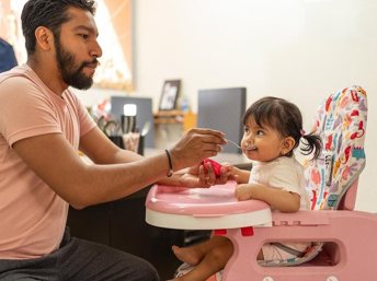 Papá dándole de comer a su hija pequeña