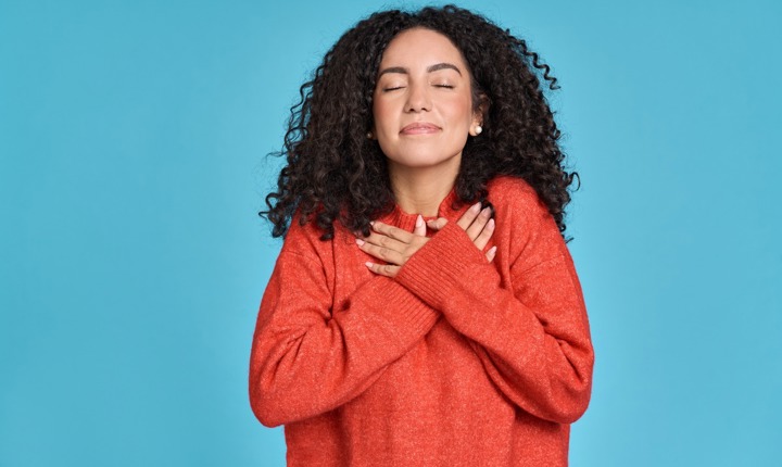 Chica latina con suéter rojo en actitud de sentirse feliz con la vida