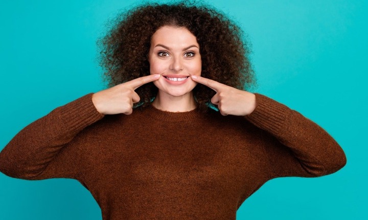 Mujer señalando su sonrisa