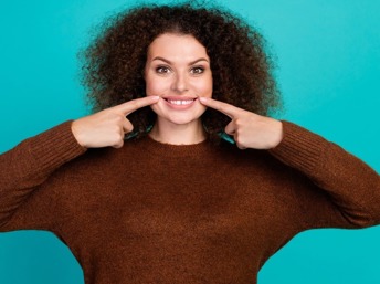 Mujer señalando su sonrisa