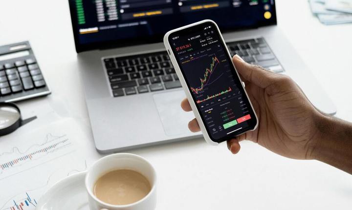 Persona usando sus dispositivos para invertir en la bolsa